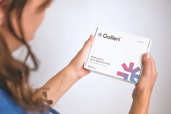 Close-up of the Galleri test box being held by a person wearing purple scrubs and a stethoscope