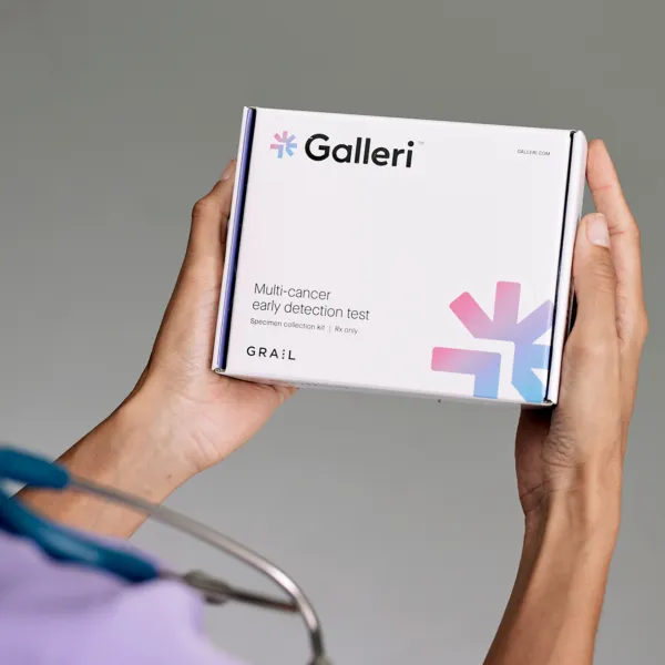 Close-up of the Galleri test box being held by a person wearing purple scrubs and a stethoscope