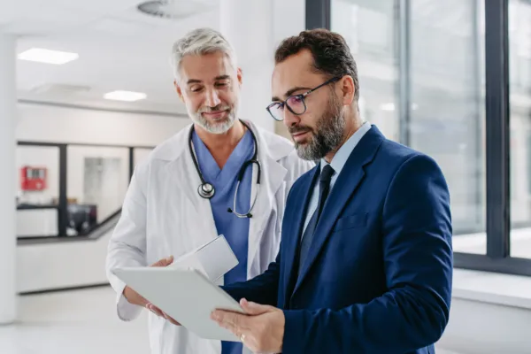 group of healthcare professionals talking and standing in front of a window with notepads