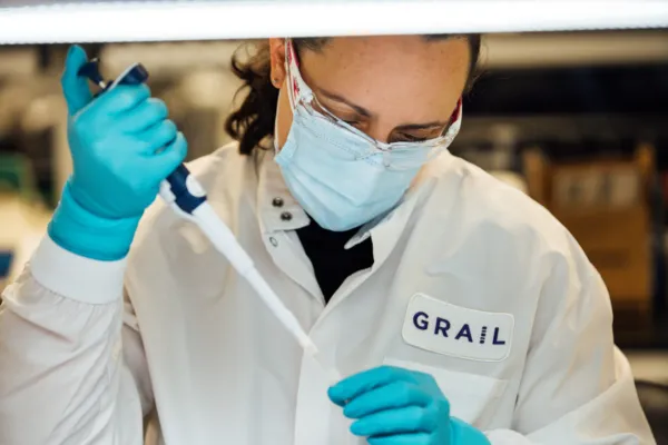 Female grail scientist in a white coat and blue gloves working in the lab